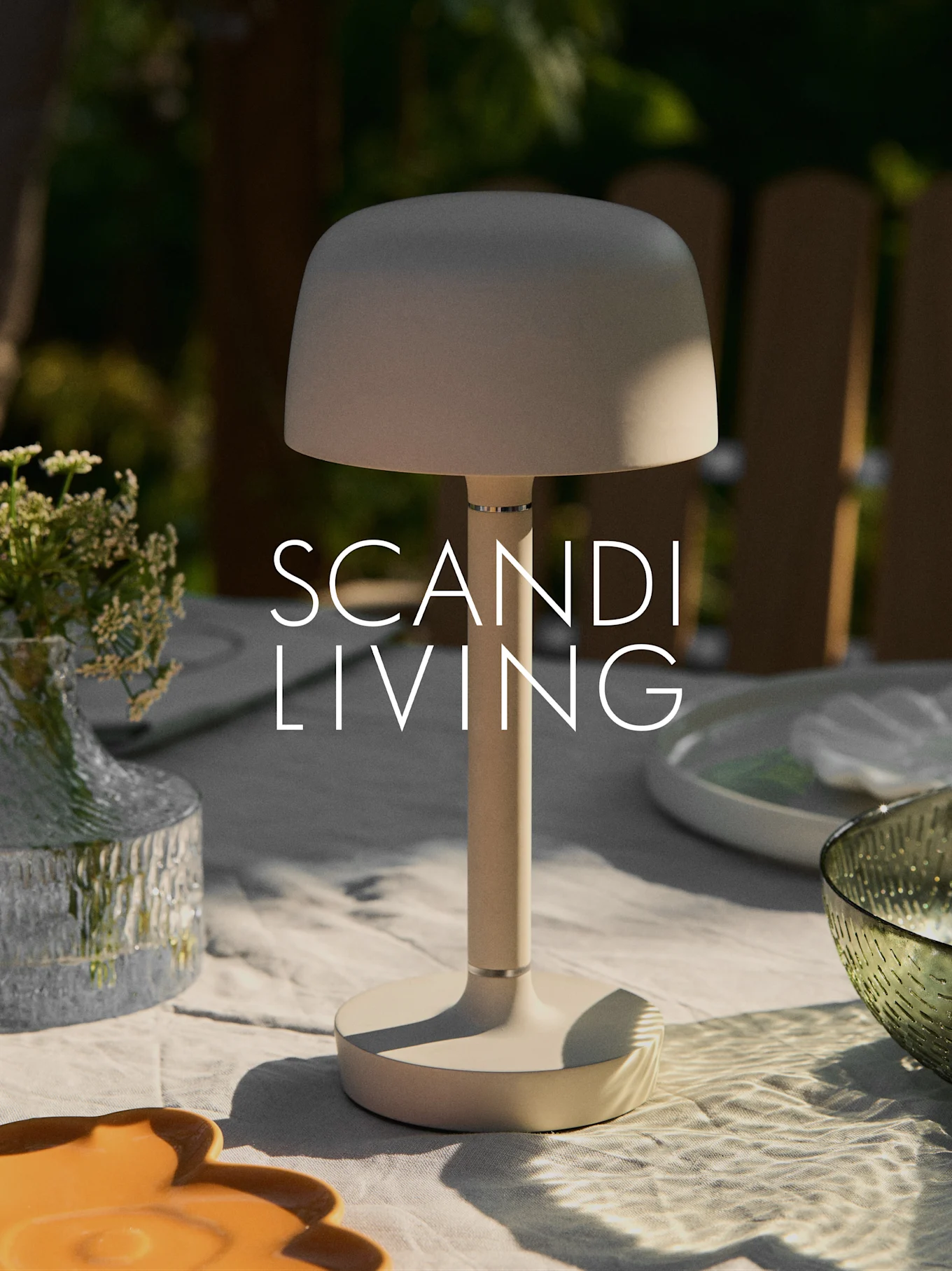 Beige moderni kannettava pöytälamppu ulkopöydällä, jossa kukkamaljakko ja astioita. Teksti "SCANDI LIVING".