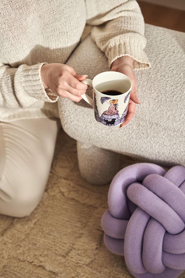 Muki, jossa on ruotsalaisen kirjailijan Elsa Beskowin aihe - Gredelin-täti merkiltä Design House Stockholm ja Fia-karahvi lasista violetilla kannella, Frame-hylly sävyssä tammi ja valkoinen.