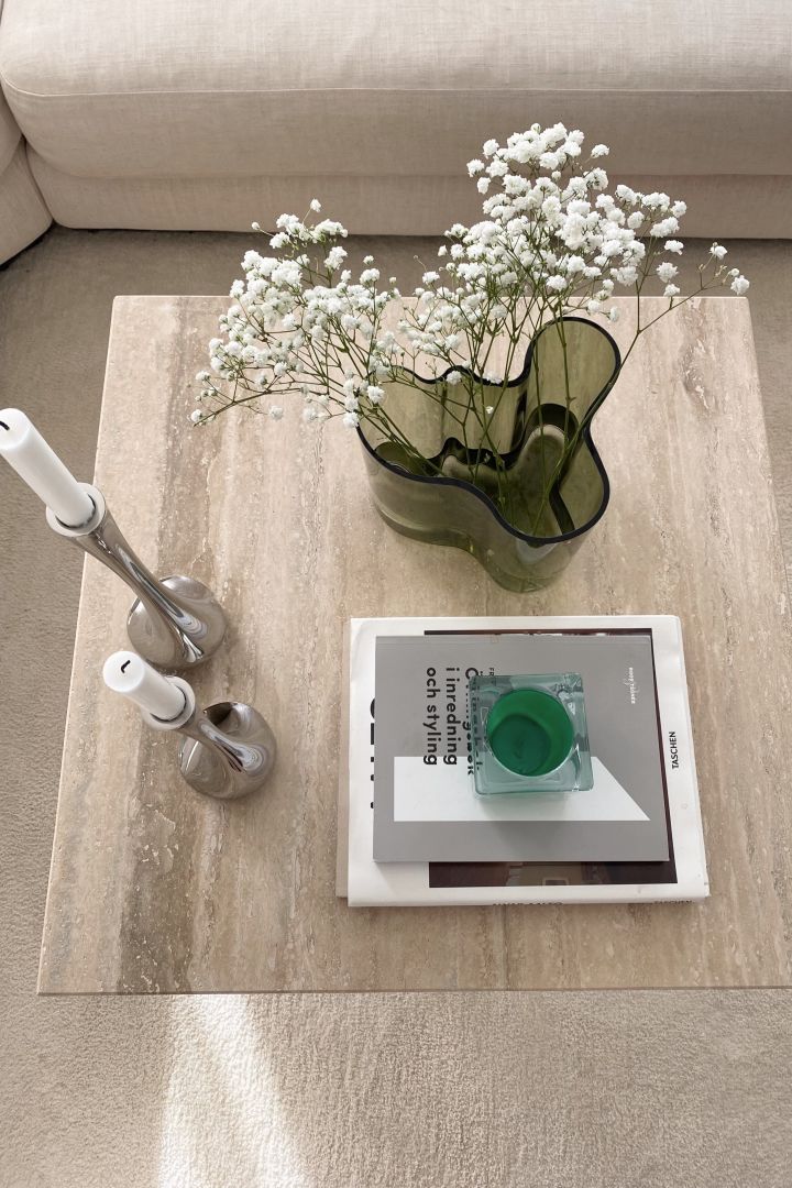 Luo viihtyisä hygge-olohuone luonnollisilla elementeillä, kuten kivisohvapöydällä tai vihreällä maljakolla, tässä Iittalan Alva Aalto -maljakko. 
