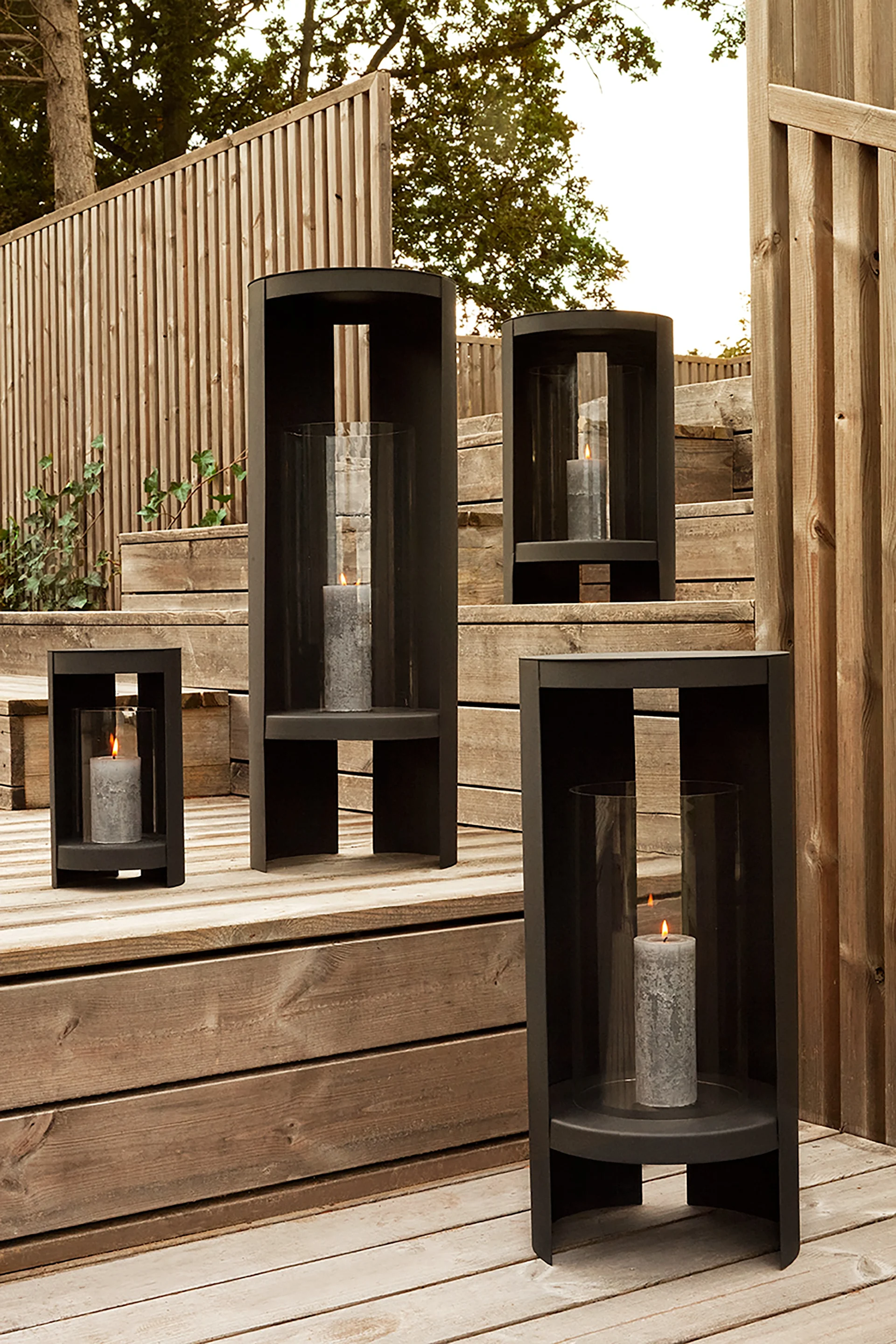 Lyhdyt ulkotiloihin - tässä näet AYTM:n Oro-lyhdyn mustana ja erikokoisena puutarhassa puuportaiden päällä.