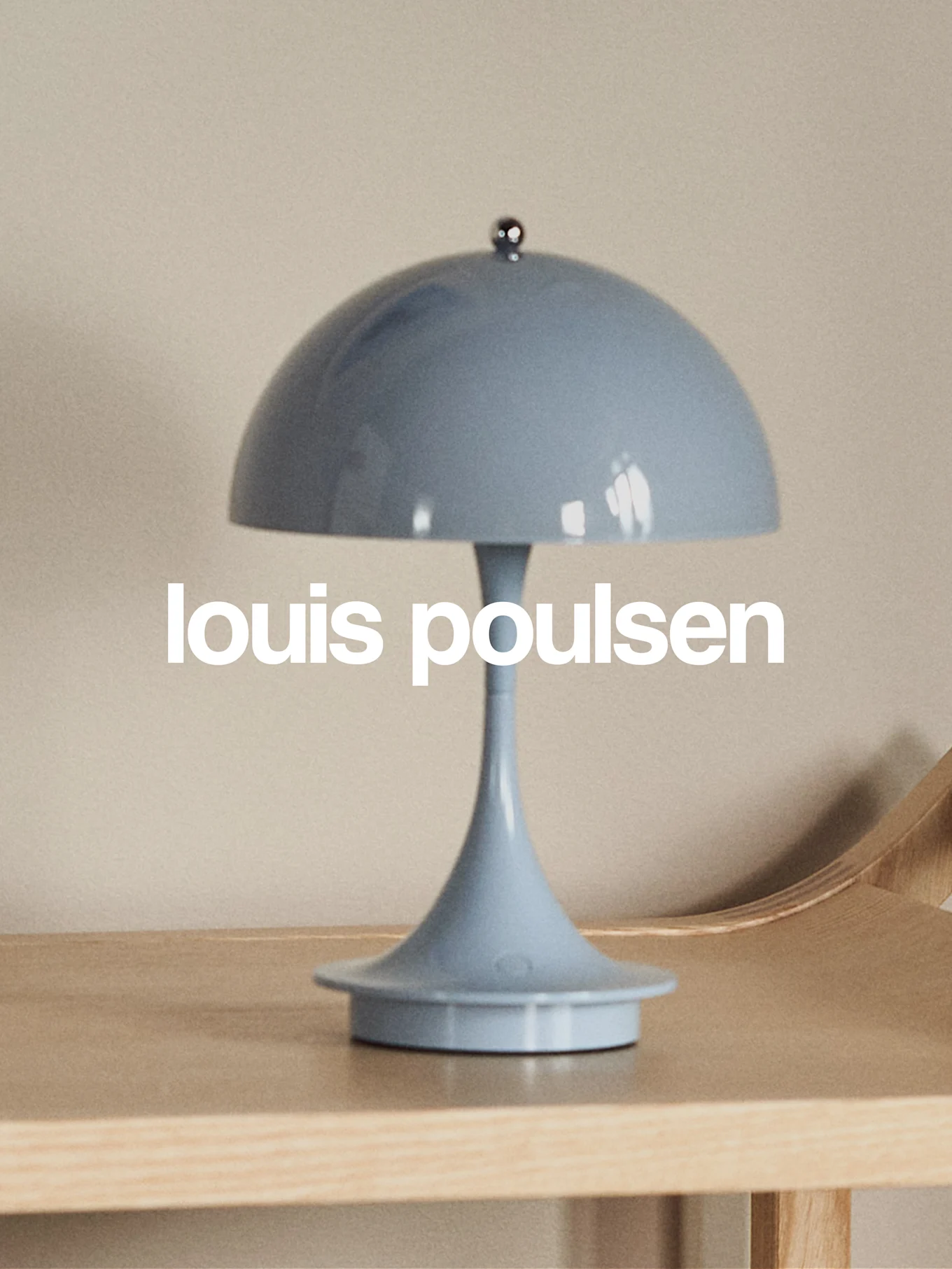 Vaaleansininen sienimäinen pöytävalaisin puupinnalla ja tekstillä 'louis poulsen'.