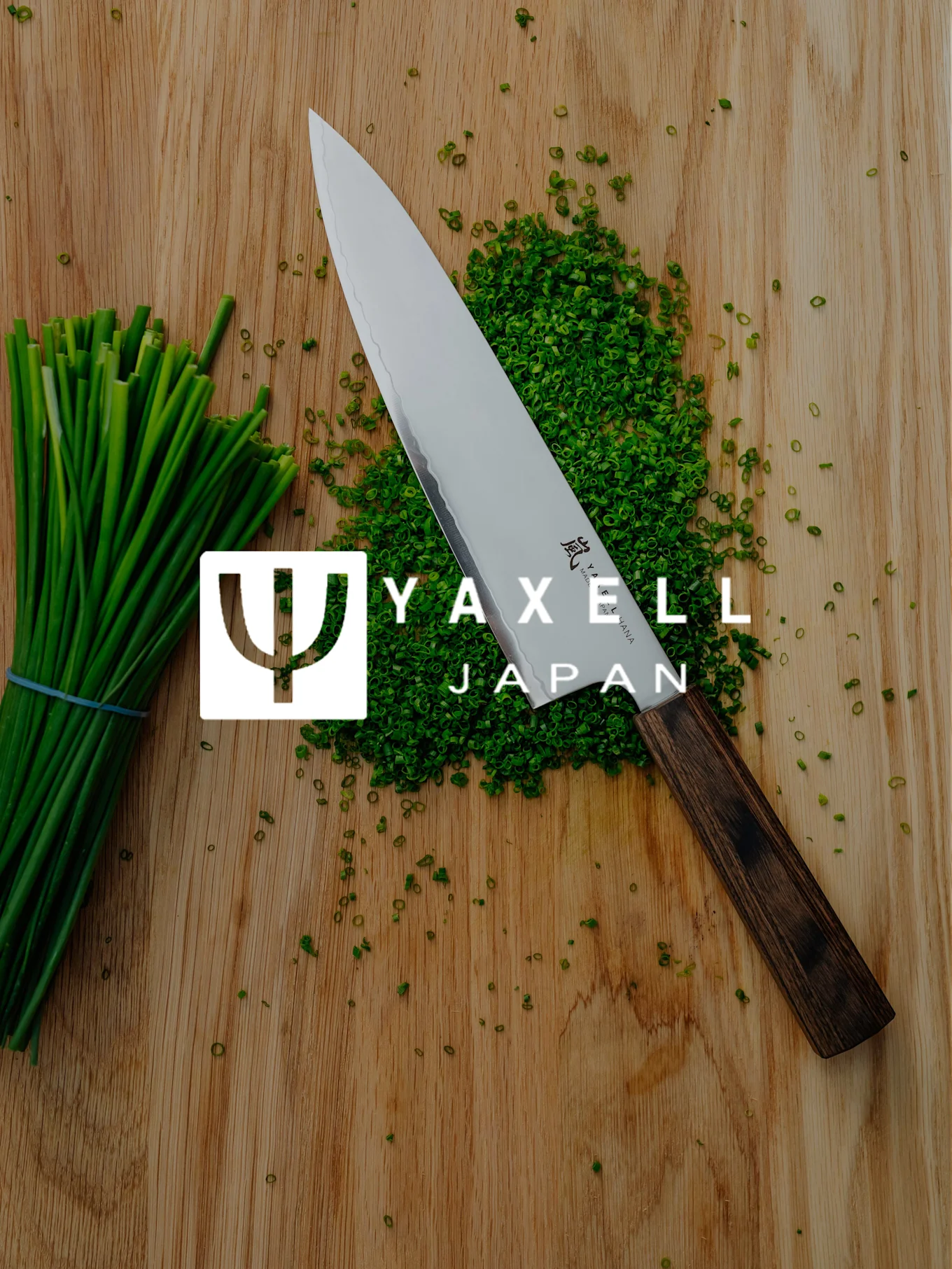 Yaxell kokkiveitsi, silputtu ruohosipuli ja ruohosipulinipusta puulaudalla, jossa Yaxell Japan -logo.