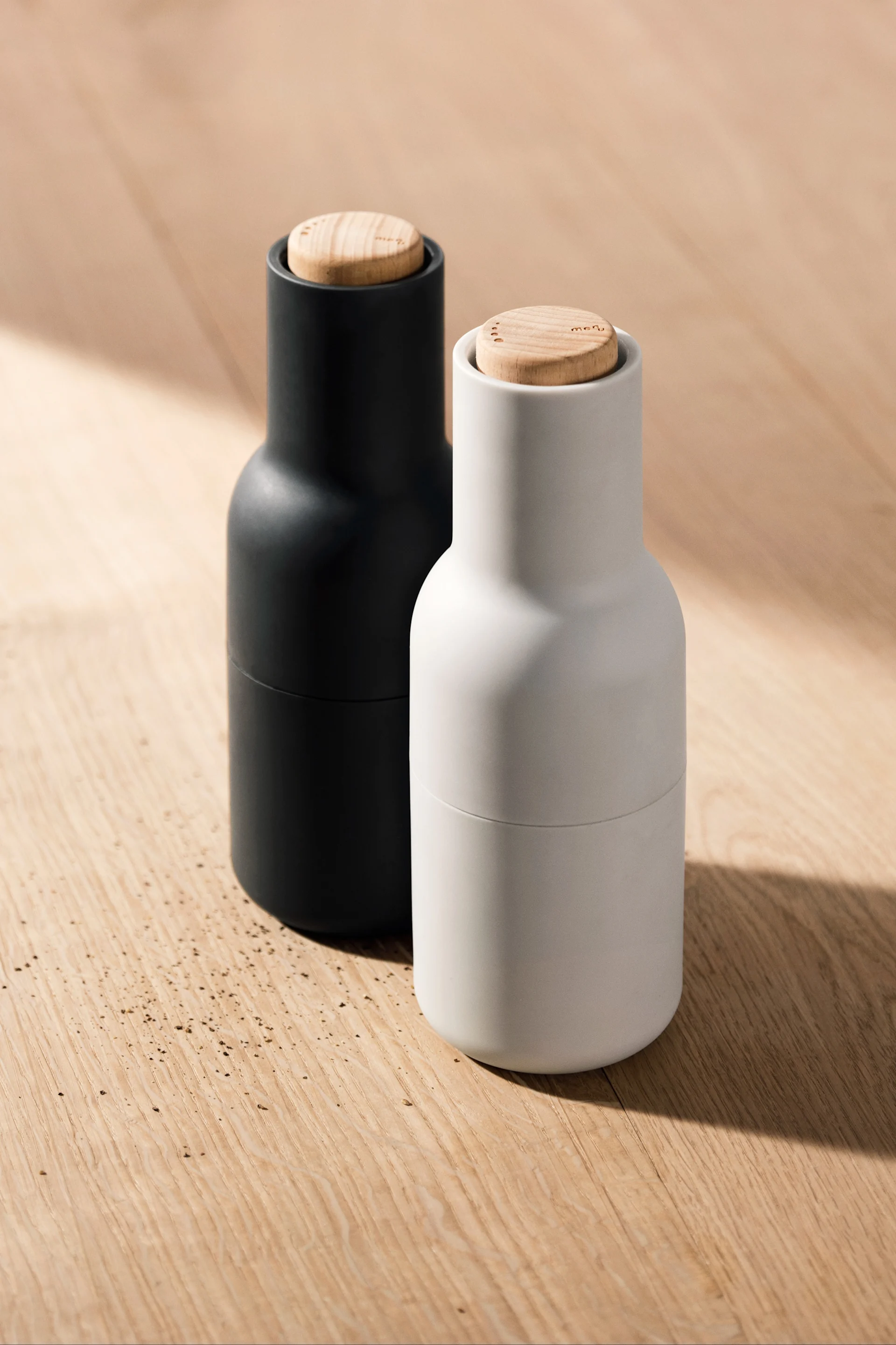 Tässä näet kaksi Audo Copenhagenin maustemyllyä puupöydällä.