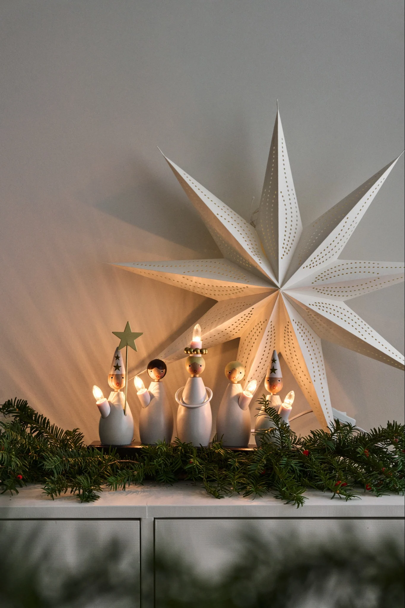 Adventtikynttiläjalusta ja lucia-kulkue loistavat lipastolla, joka on koristeltu kuusenoksilla.