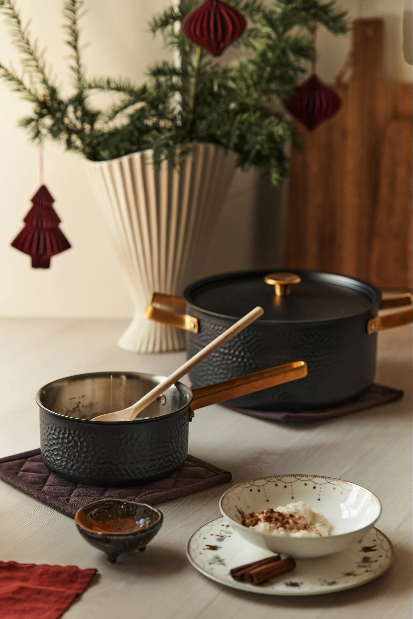 Adventiaamiainen katettu ensimmäiselle adventille Viggo-kattilalla Vargen & Thorilta. Pöydällä kattila seisoo riisipuuroa, piparkakkuja ja siirappikulhoa sisältävän lautasen vieressä, ja taustalla on joulukuusi maljakossa.