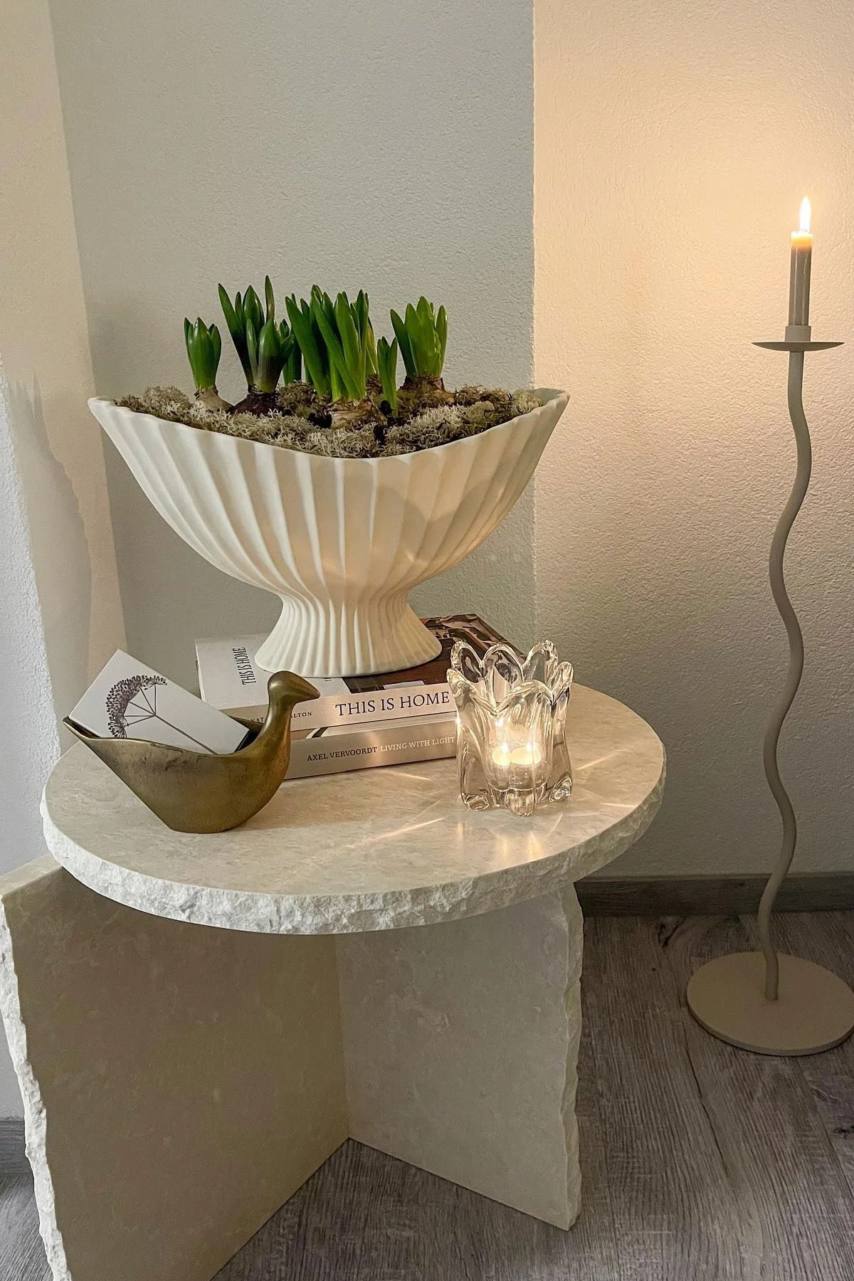 Mineral Sculptural -pöytä on koristeltu Fountain-kulholla, molemmat Ferm Livingiltä, sekä muilla pienillä esineillä. Sen vieressä on Cooee Designin suuri Curved-kynttilänjalka.