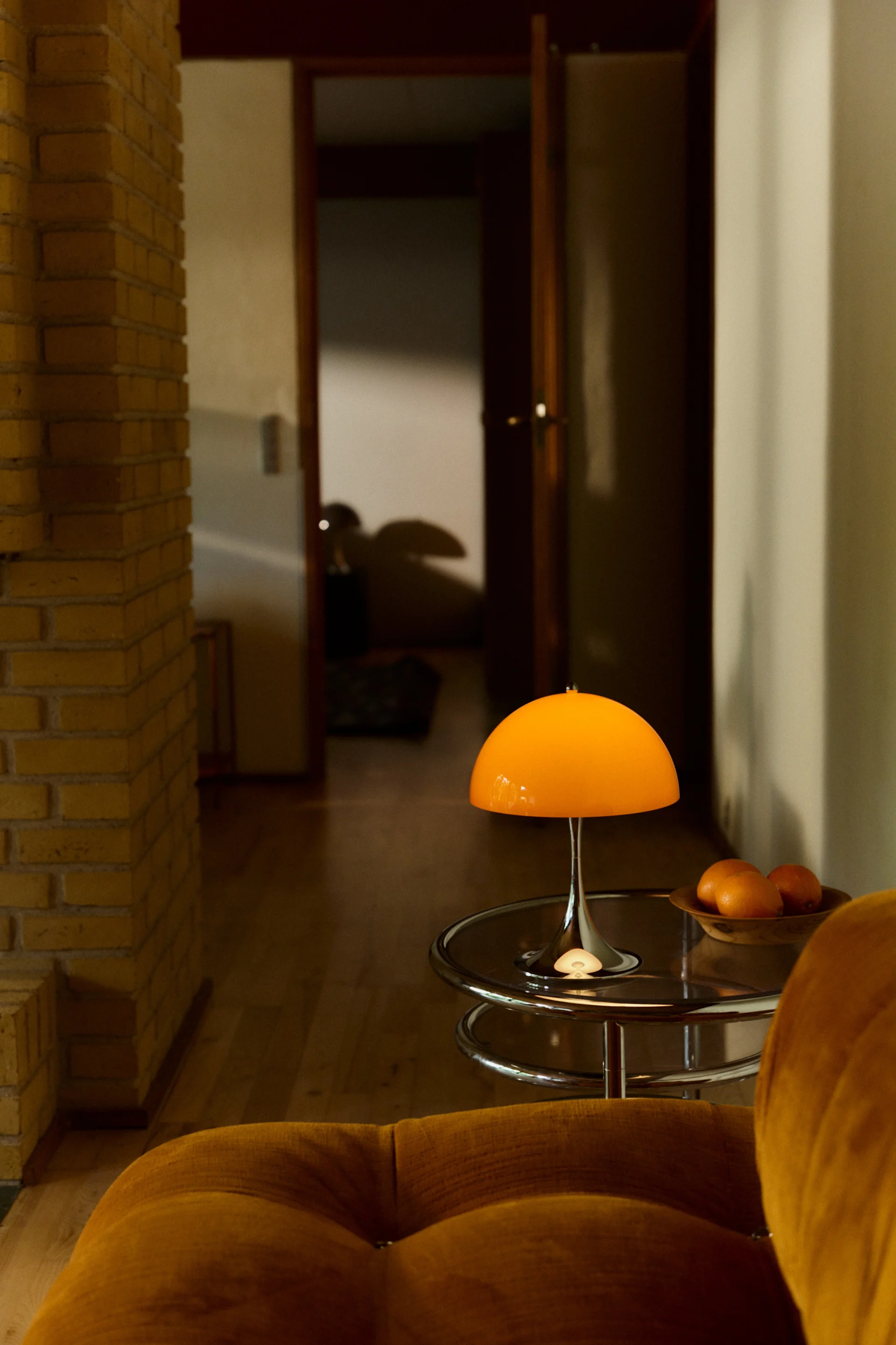 Panthella 250 -ladattava lamppu seisoo kromatulla sivupöydällä ja loistaa.
