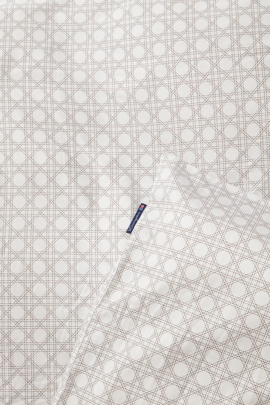 Valkoinen kangas, jossa on vaaleanruskea rottinkikuvio ja sininen Lexington-etiketti.