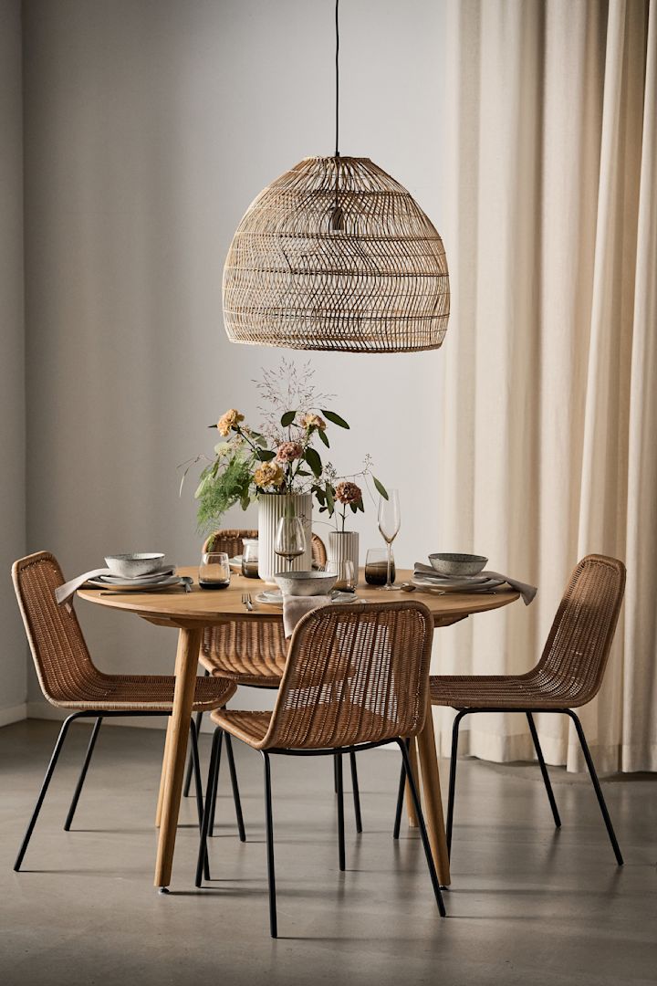 Boho-tyylinen ruokailutila, jossa on bastista valmistettu lamppu ja pyöreä pöytä sekä neljä Hapur-tuolia House Doctorilta.