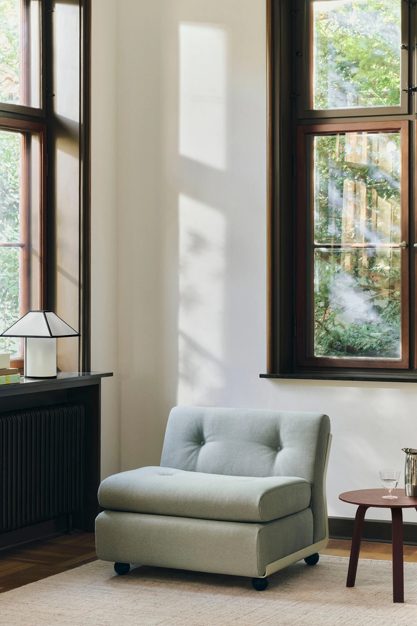 Pyöreä sohvamoduuli, joka on sijoitettu huoneeseen, jossa on suuret ikkunat, esittelee vuoden 2026 sisustustrendejä.