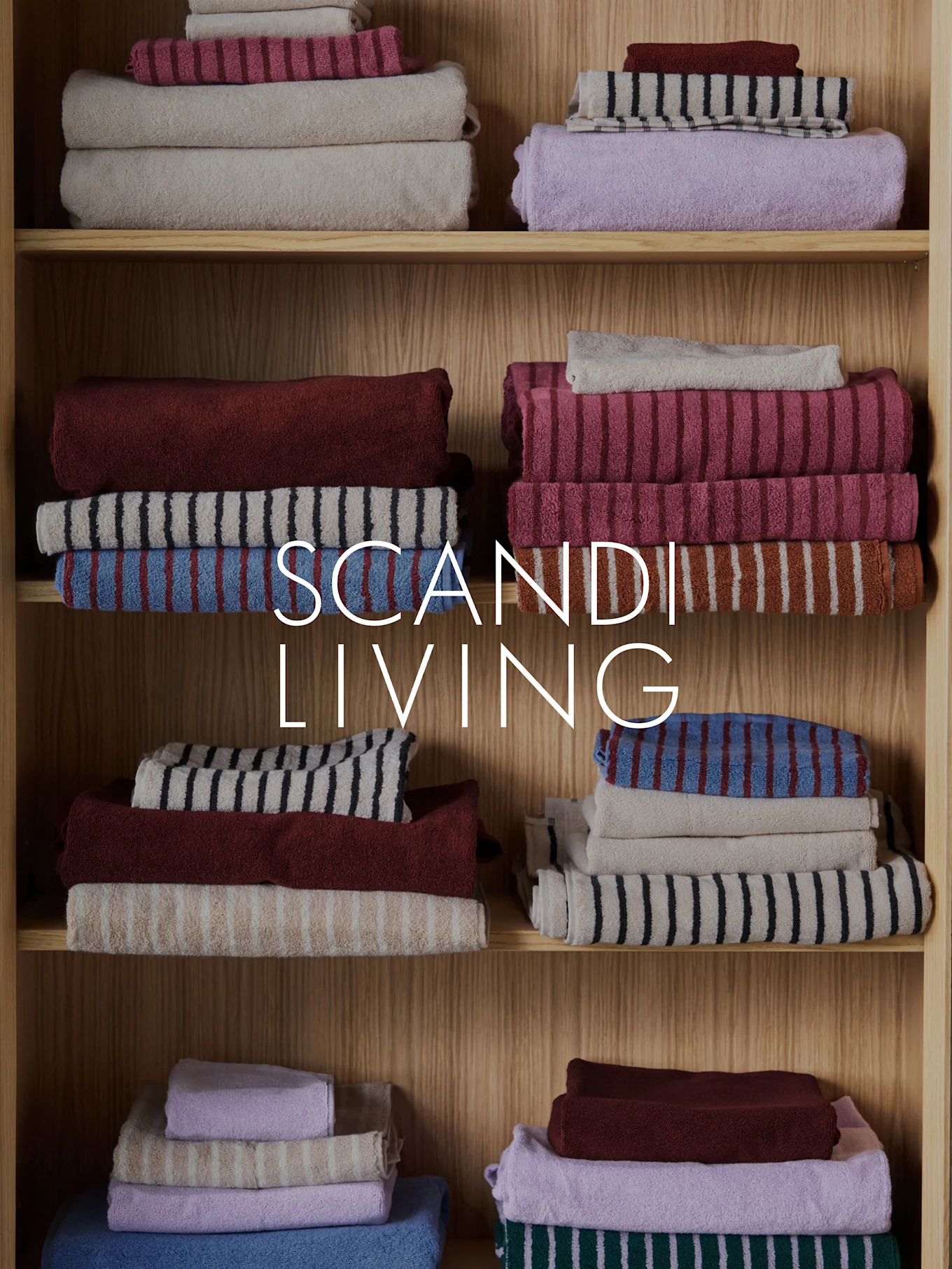 SCANDI LIVING -teksti pinottujen, taiteltujen pyyhkeiden päällä eri väreissä ja kuvioissa puuhyllyillä.