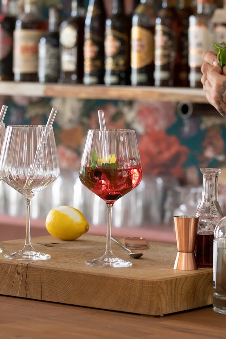 Nachtmann Feel Good G&T -lasissa oleva mocktail seisoo puulevyllä baarin edessä.