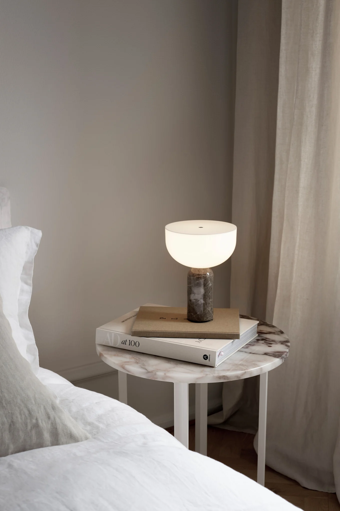 Kizu-ladattava lamppu seisoo yöpöydällä sängyn vieressä.
